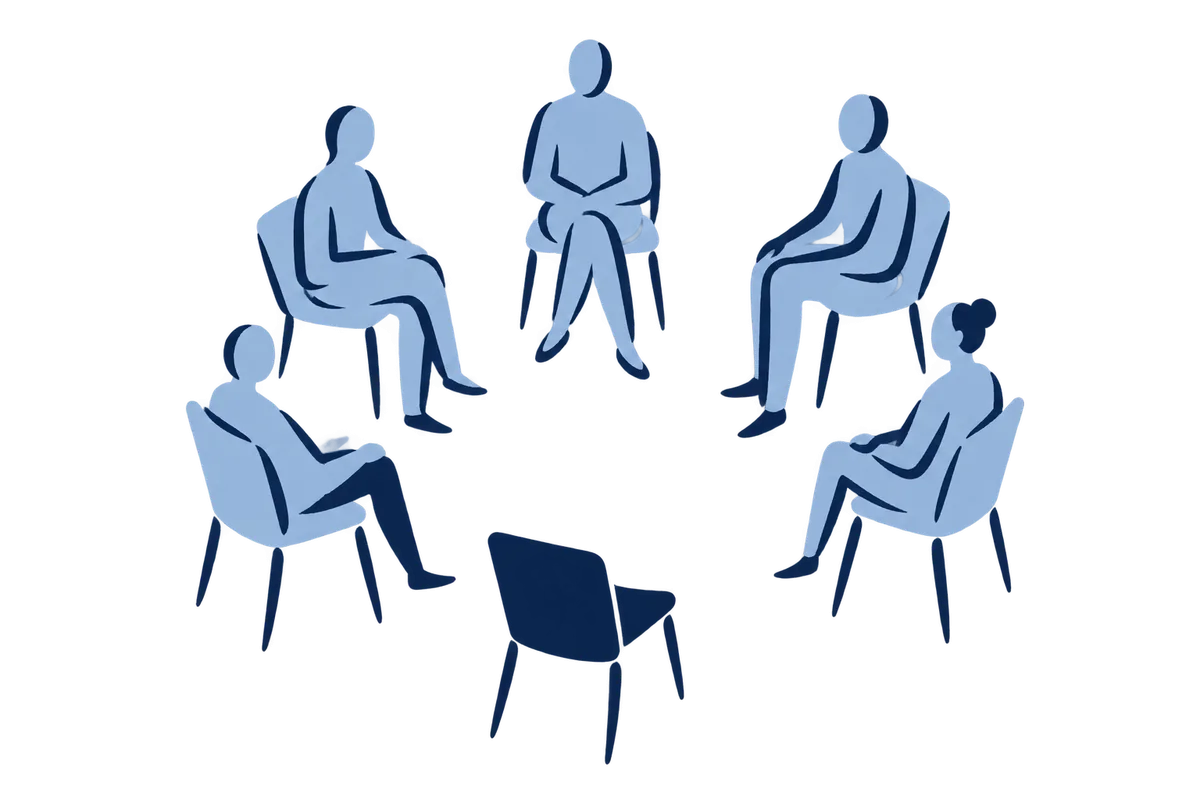 Six chairs in a circle, five people seated, one chair turned outward and empty.